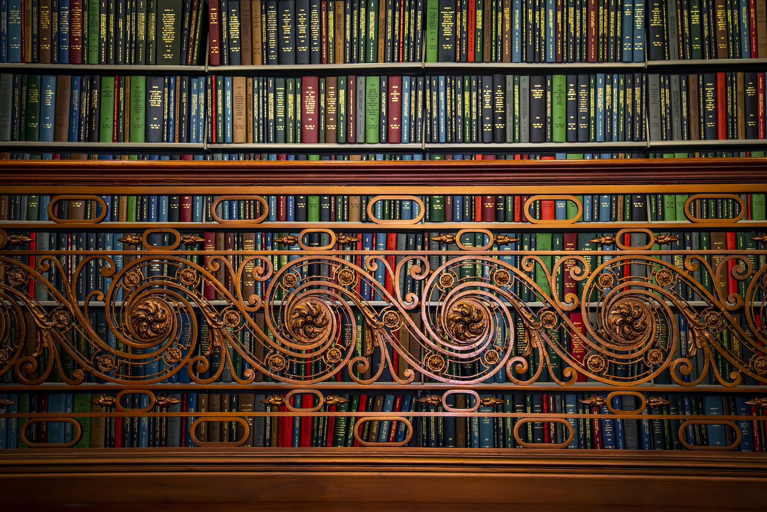 Library stacks as seen behind an ornate balcony railing at CUNY Graduate Center Library