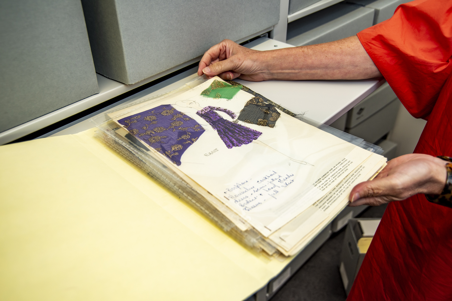 Hands demonstrating a book of clothing patterns at FIT Library